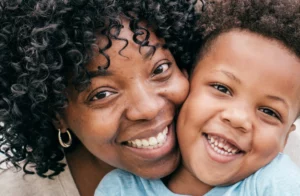African American mother and preschool son cheek to cheek and smiling.