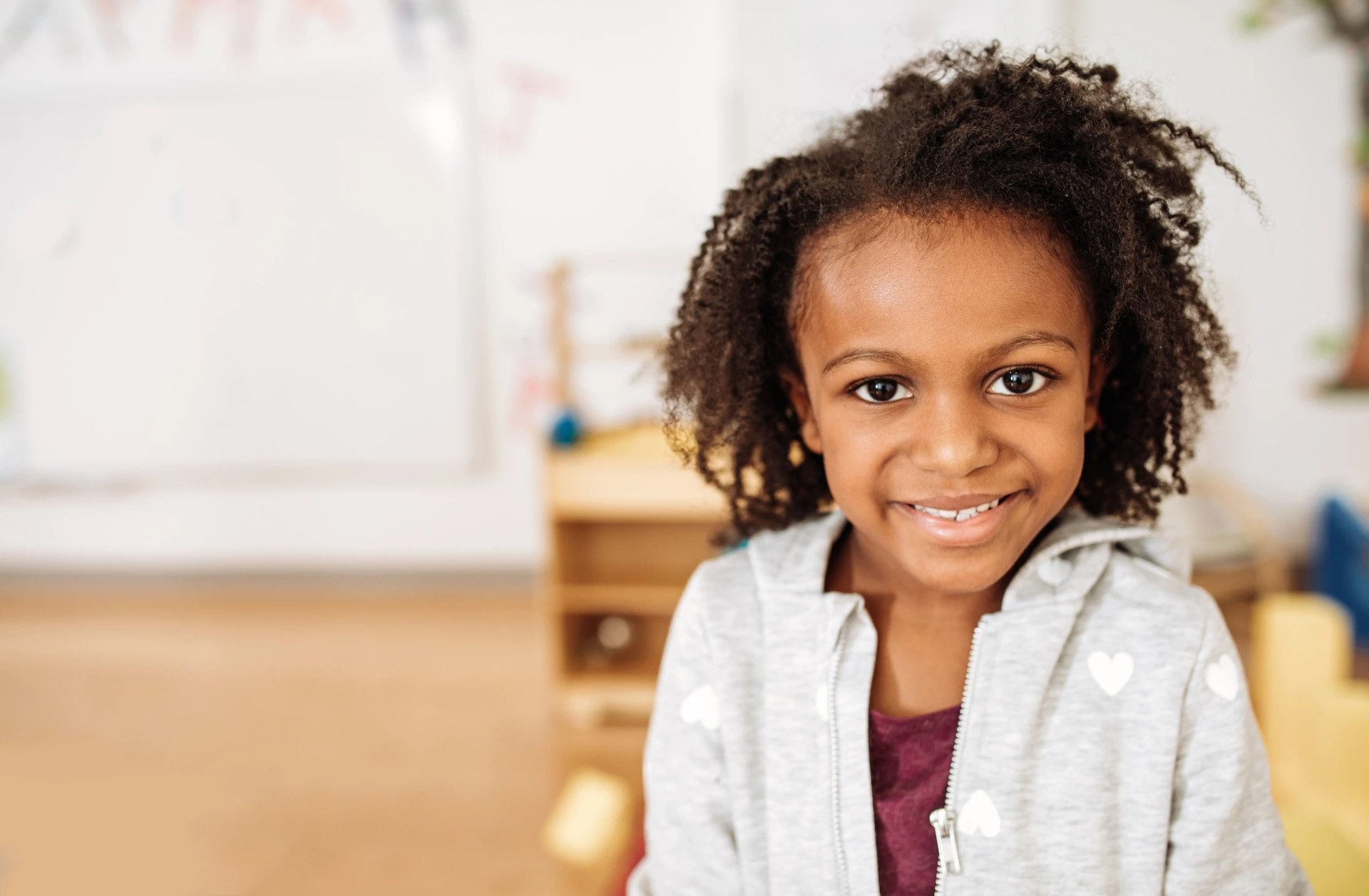 African American girl smiling in a preschool classroom.