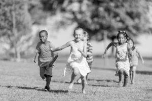 A diversity of children running across a field together.