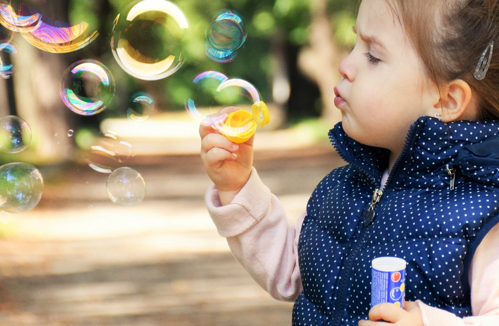 Close up of a preschool-age girl blowing bubbles.